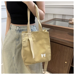 Detail of khaki canvas bag with white bow print and adjustable shoulder strap