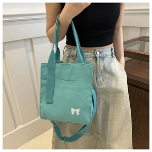Detail of mint green canvas bag with white bow print and adjustable shoulder strap