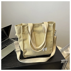 Detail of khaki canvas tote bag with white bow print and adjustable woven strap