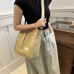 Minimalist khaki canvas tote bag with bow pattern and wide adjustable shoulder strap