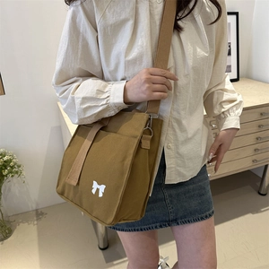 Brown canvas crossbody bag with white bow pattern and adjustable wide woven shoulder strap