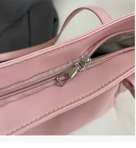 Close-up of a smooth silver zipper on a pink leather tote bag with interior lining details