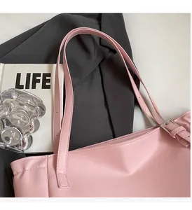 Detail view of pink leather tote bag featuring adjustable metal buckle and durable handle