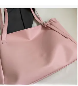 Detailed macro view of pink synthetic leather tote with silver metal buckle and strap