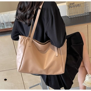 Close-up of beige large capacity tote bag worn on shoulder by a model in a cafe