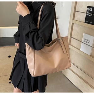 Close-up of beige faux leather tote bag showing fine texture and silver buckle detail
