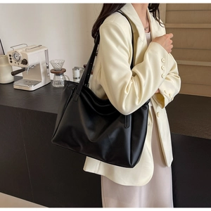 Close-up of a large black matte tote bag in a cozy cafe setting for daily commute