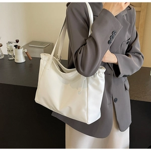Detail of white leather tote bag with elegant side pleats on an office desk