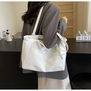 Close-up of minimalist white large-capacity tote bag worn on shoulder by a model