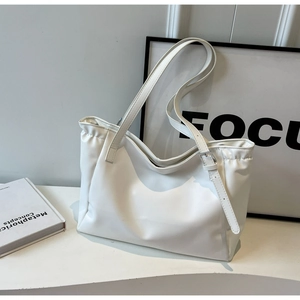 Detail of white tote bag with natural pleats, adjustable strap and silver metal buckle