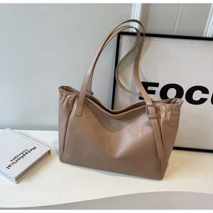 Detailed close-up of beige faux leather tote bag showing adjustable straps and metal buckles