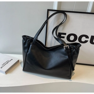 Detail of black faux leather tote bag with silver buckle and smooth textured finish