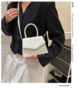 Minimalist white trapezoidal handbag with V-flap and detachable strap on a model