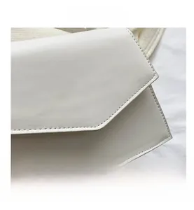 Detail of white leather envelope bag with fine stitching and refined texture
