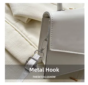 Close-up of white leather handbag featuring durable silver metal hooks and adjustable strap