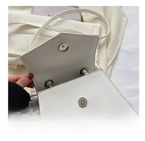 Detail of white PU leather handbag featuring a secure silver magnetic snap closure
