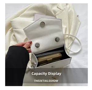 Detail of white leather bag capacity showing a large phone and a long wallet inside
