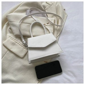 Detail of white trapezoid shoulder bag with magnetic flap on a tweed blazer jacket