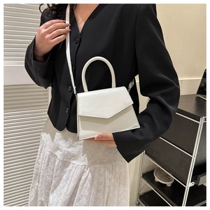 Mini white leather crossbody bag shown on a model with a black blazer and white skirt