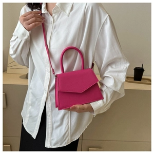 Detail of structured rose pink trapeze handbag with V-shaped flap and leather handle