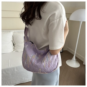 Detail of light purple crescent tote bag featuring colorful embroidered patterns and wide strap