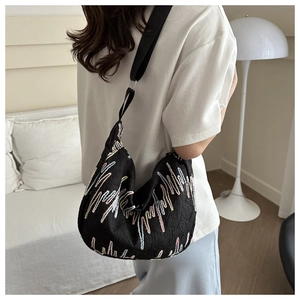 Detail of black dumpling bag with colorful zigzag embroidery on a model at home
