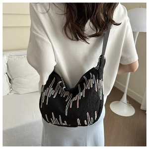 Detail of black crescent bag with colorful wave embroidery and pleated fabric texture