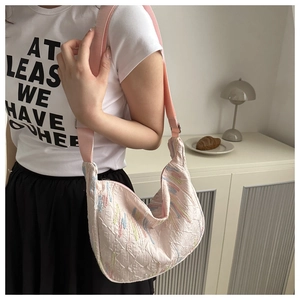 Detail of pink croissant bag with embossed logo patterns and colorful embroidery accents