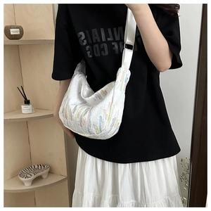 Detail of white pleated tote bag with colorful embroidery and adjustable nylon strap