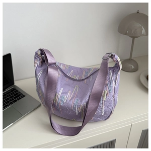 Detail of purple crescent moon bag featuring textured F-pattern fabric and wide strap