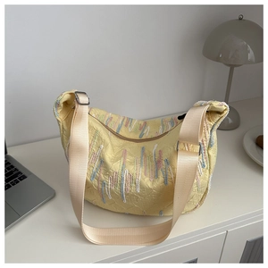 Detail of yellow crescent tote bag featuring embroidered wavy textures and wide strap
