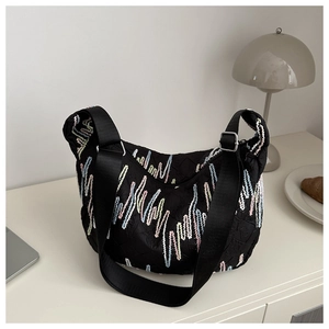 Detail of colorful wavy embroidery on black textured tote bag with fabric shoulder strap