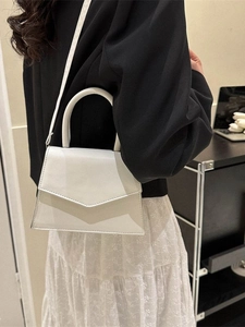 Minimalist white leather top handle bag with V-shaped flap shown on a fashion model