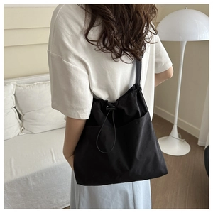 Detail of a large black nylon bucket bag showing the drawstring closure and outer pockets