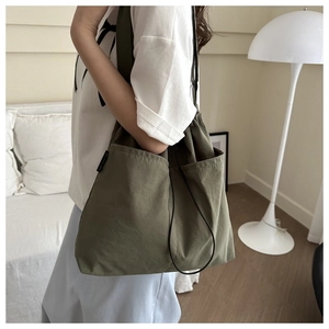 Detail of olive green nylon bucket bag featuring a drawstring closure and side pocket