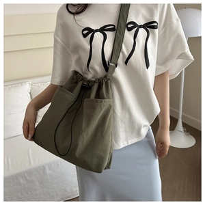 Olive green nylon tote bag on a model showing the spacious pockets and drawstring design