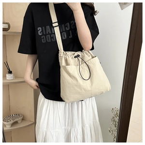 Detailed view of beige nylon drawstring bucket bag with adjustable strap on a model