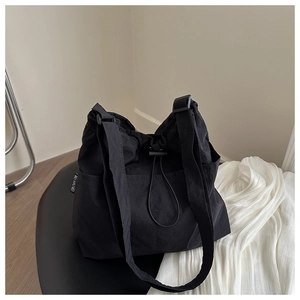 Detail of black nylon bucket bag featuring a drawstring closure and adjustable strap