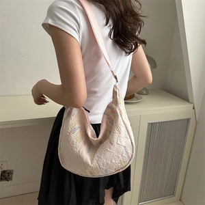 Pink quilted half-moon shoulder bag with colorful embroidery and wide fabric strap