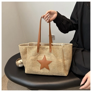 Detail of hollow woven tote bag featuring a brown leather star patch and durable handles
