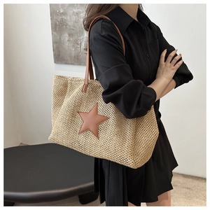Detail of hand-woven tote bag with brown star patch on model in a casual setting
