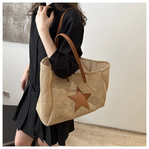 Macro detail of straw woven tote bag featuring a leather star patch and leather handles