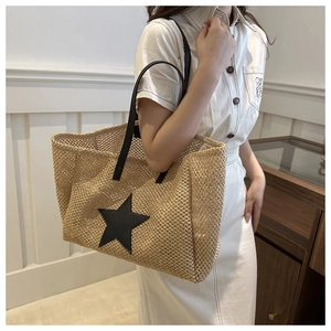 Close-up of a straw tote bag with a black leather star patch and durable leather straps