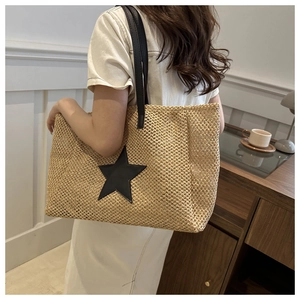 Detail of woven straw tote bag with black star patch and slim shoulder straps