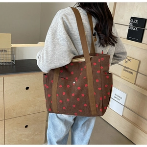 Détail du sac cabas en velours côtelé marron avec imprimé fraise et poche à bouton
