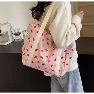 Détail du sac fourre-tout rose en velours côtelé avec imprimé fraise et bandoulière