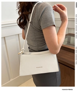 Dettaglio borsa baguette bianca con scritta FASHION dorata e tracolla in corda intrecciata
