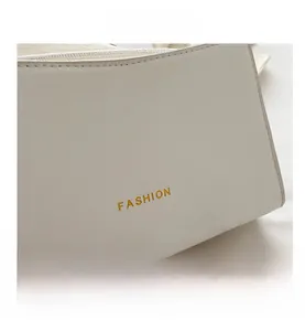 Dettaglio della borsa in similpelle bianca con cuciture fini e scritta FASHION dorata