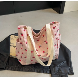 Sac cabas en velours côtelé rose imprimé fraise avec anses crème posé sur une veste