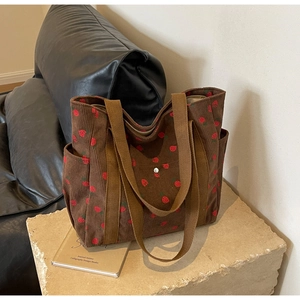 Détail du sac fourre-tout en velours marron à motif fraise et large bandoulière